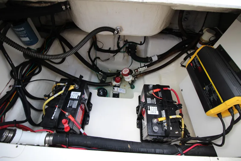 Slide: The Image of 2021 Robalo R230 Center Console boat battery compartment with wiring and charger. - 79