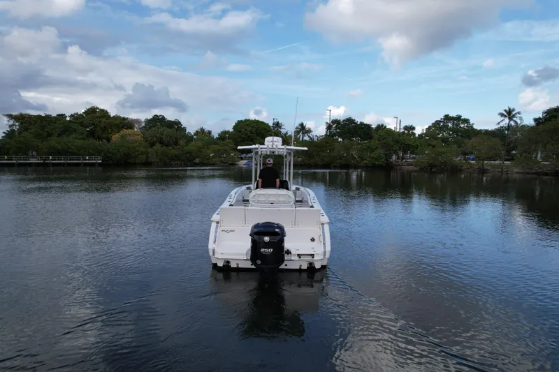 Slide: The Image of 2021 Robalo R230 Center Console boat on calm water, surrounded by lush greenery. - 9