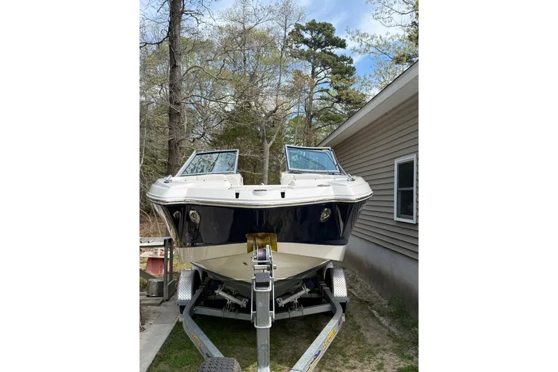 Slide: The Image of 2016 Chaparral 224 Sunesta boat on trailer beside house, surrounded by trees. - 10