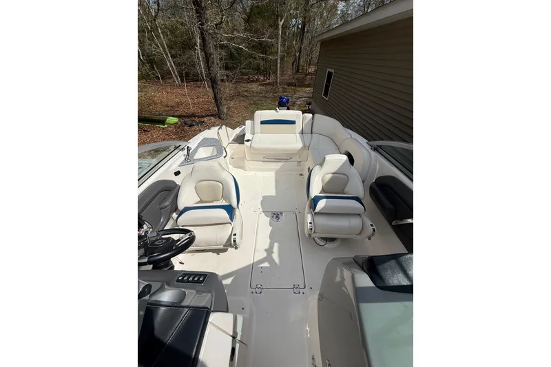 Slide: The Image of 2016 Chaparral 224 Sunesta boat interior with white and blue seating, parked outdoors. - 19