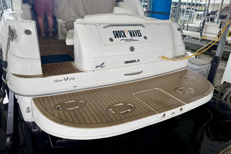 Slide: The Image of 2001 Sea Ray 340 Sundancer boat docked, featuring teak swim platform and "Shock Waves" nameplate. - 2