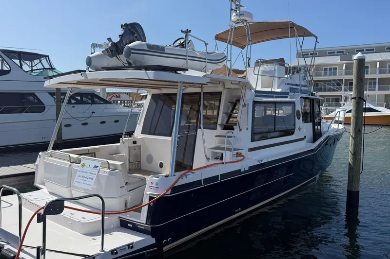The Image of 2026 Ranger Tugs R-43 CB yacht docked at marina, featuring upper deck and dinghy. - 0