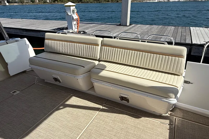 Slide: The Image of 2026 Ranger Tugs R-43 CB boat seating area with beige cushions by the dock. - 12