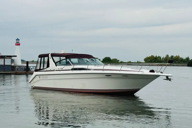Slide: The Image of 1991 Sea Ray Sundancer 350 yacht docked near a lighthouse on calm water. - 11