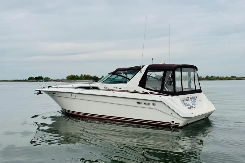 Slide: The Image of 1991 Sea Ray Sundancer 350 boat on calm water, featuring sleek design and white exterior. - 3