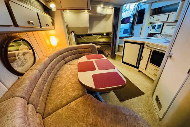 Slide: The Image of Interior of a 1991 Sea Ray Sundancer 350, featuring cozy seating and a compact kitchen. - 30