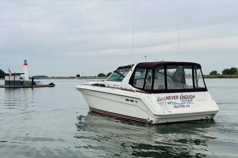 Slide: The Image of 1991 Sea Ray Sundancer 350 boat on calm water near a small lighthouse. - 4