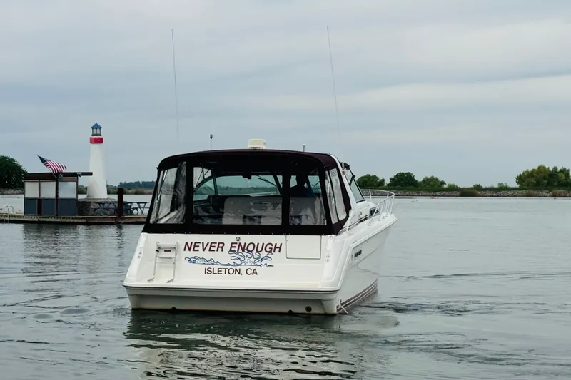 Slide: The Image of 1991 Sea Ray Sundancer 350 boat named "Never Enough" on water near a lighthouse. - 7