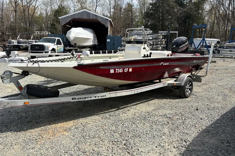 The Image of 2016 Ranger RB190 boat on trailer, parked outdoors with trees and vehicles in the background. - 0
