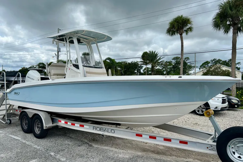 Slide: The Image of 2026 Boston Whaler 250 Dauntless on trailer, blue hull, cloudy sky. - 2