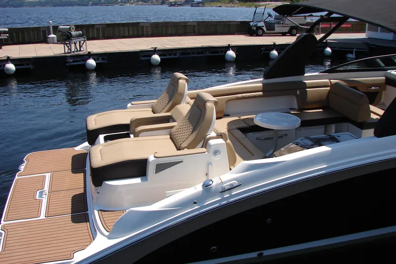 Slide: The Image of 2018 Sea Ray SDX 290 boat with luxurious seating and table, docked by the water. - 11