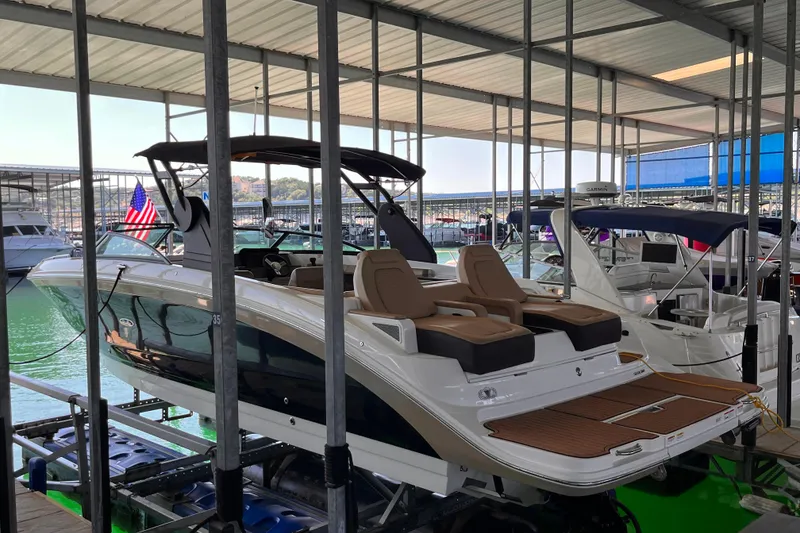 Slide: The Image of 2018 Sea Ray SDX 290 boat docked in a marina with covered roof. - 2