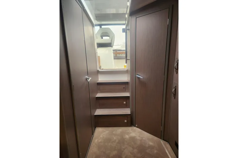 Slide: The Image of Interior view of 2025 Beneteau Gran Turismo 32 yacht with wooden stairs and door. - 32