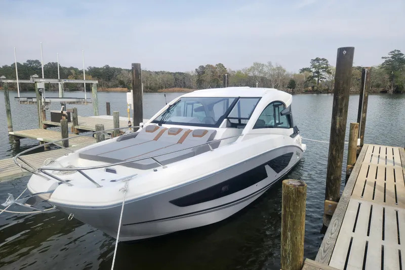Slide: The Image of 2025 Beneteau Gran Turismo 32 docked at a serene lakeside marina. - 6