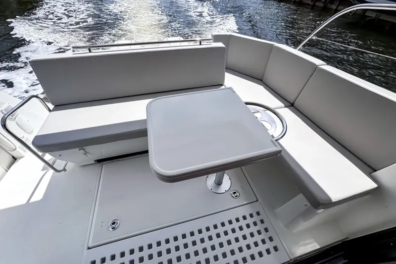 Slide: The Image of 2023 Beneteau Antares 11 boat deck with seating and table, on water. - 12