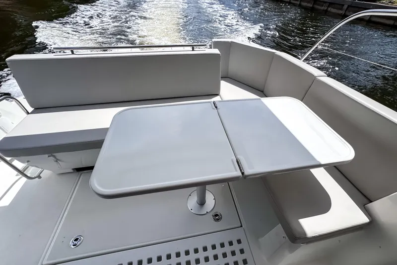 Slide: The Image of 2023 Beneteau Antares 11 boat deck with seating and table, cruising on water. - 13