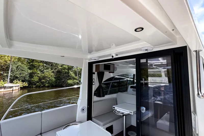 Slide: The Image of 2023 Beneteau Antares 11 interior with seating, table, and sliding glass door by the water. - 14