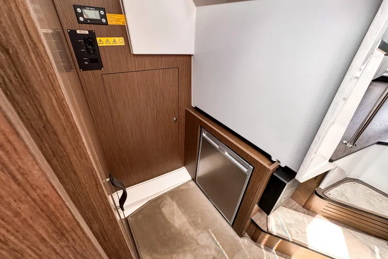 Slide: The Image of Interior of 2023 Beneteau Antares 11, featuring wood paneling and compact refrigerator. - 37