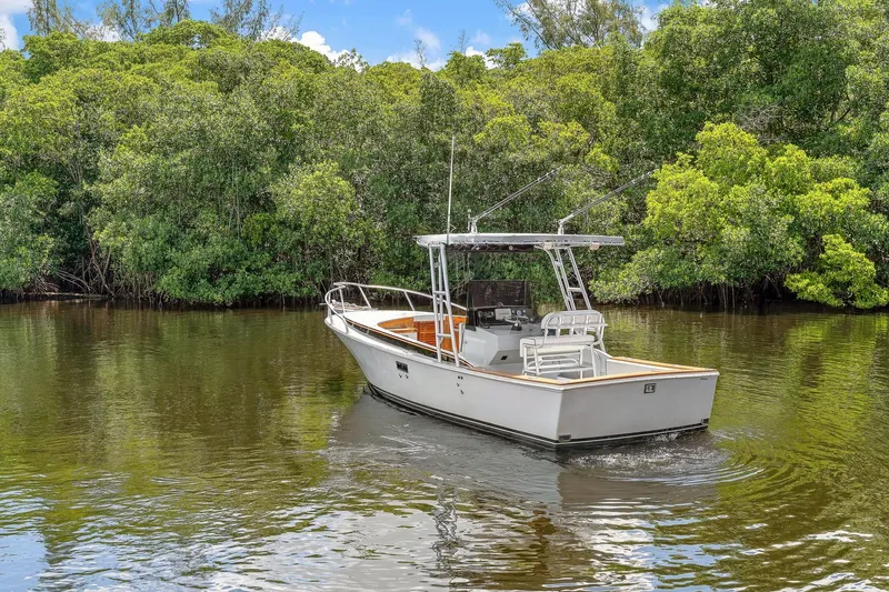Slide: The Image of 2024 Strike 26 Center Console Cuddy boat cruising in a lush, green waterway. - 31