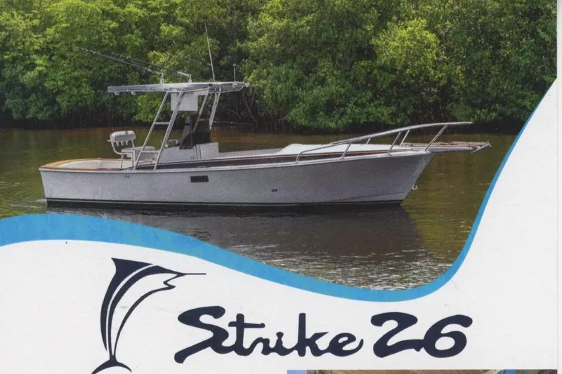 Slide: The Image of 2024 Strike 26 Center Console Cuddy boat on calm water, surrounded by lush greenery. - 32