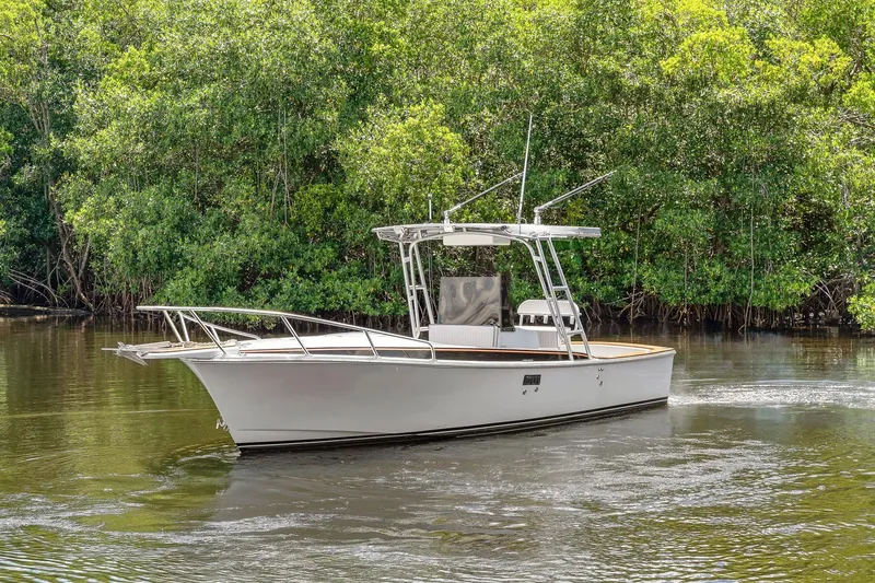 The Image of 2024 Strike 26 Center Console Cuddy boat cruising on a calm river near lush greenery. - 0