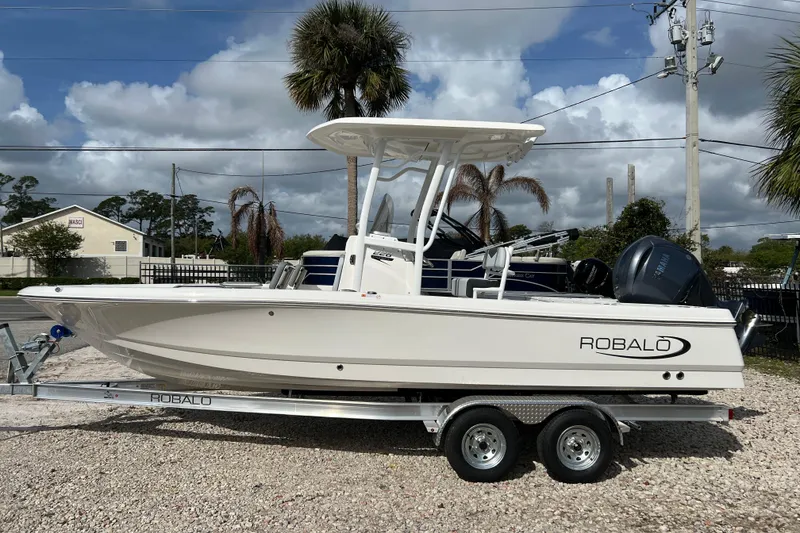 The Image of 2026 Robalo 226 Cayman boat on trailer, parked outdoors under cloudy sky. - 1