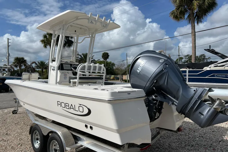 Slide: The Image of 2026 Robalo 226 Cayman boat with Yamaha outboard motor on trailer, parked outdoors. - 2