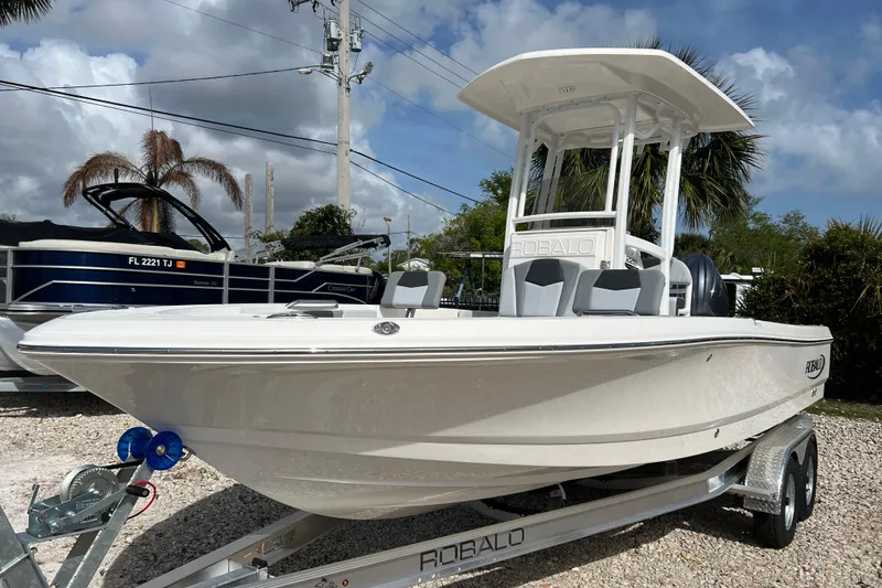 Slide: The Image of 2026 Robalo 226 Cayman boat on trailer, displayed outdoors under a cloudy sky. - 8