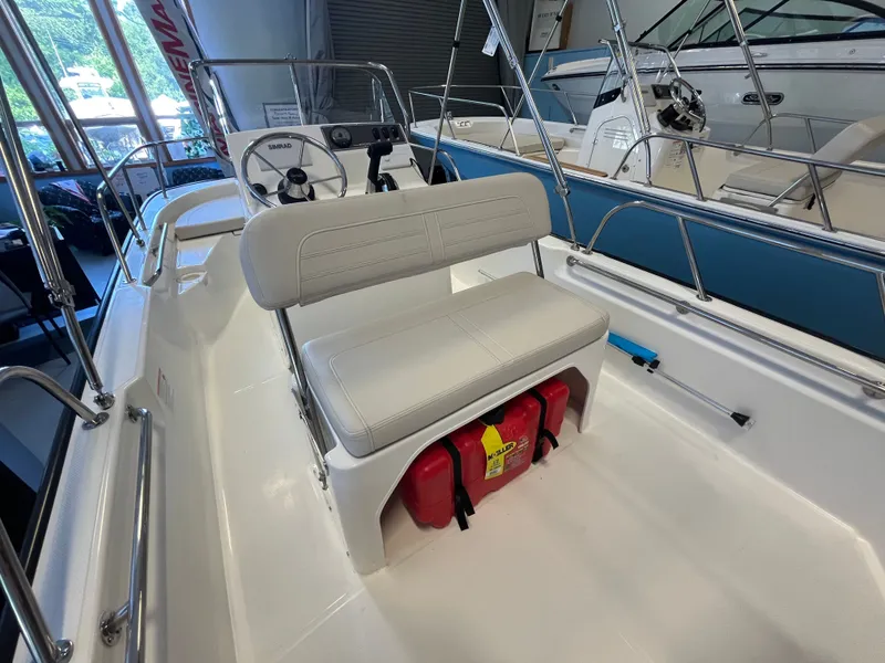Slide: The Image of The image shows the cockpit of a Boston Whaler 150 Montauk with white seating and a red fire extinguisher. - 5