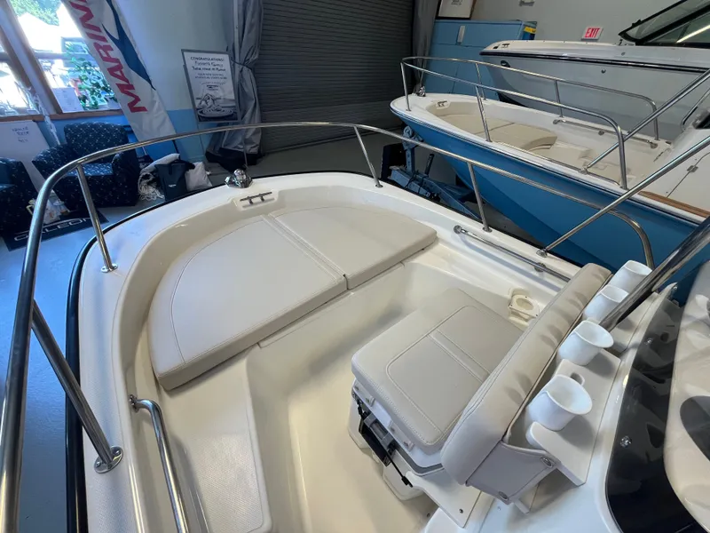 Slide: The Image of The image shows the cockpit of a Boston Whaler 150 Montauk with beige cushions and stainless steel railing. - 7
