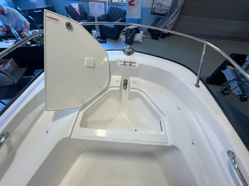 Slide: The Image of The image shows the bow area of a Boston Whaler 150 Montauk with an open storage compartment. - 9