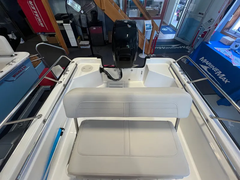 Slide: The Image of Interior view of a Boston Whaler 150 Montauk with white bench seat and helm console. - 2