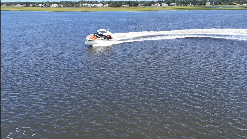 Slide: The Image of A 2027 Saxdor 320 GTO speeds across the water, with a shoreline in the background. - 2