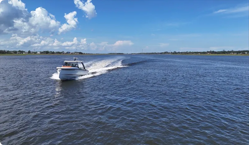 Slide: The Image of A 2027 Saxdor 320 GTO speeds across a wide body of water under a blue sky. - 43