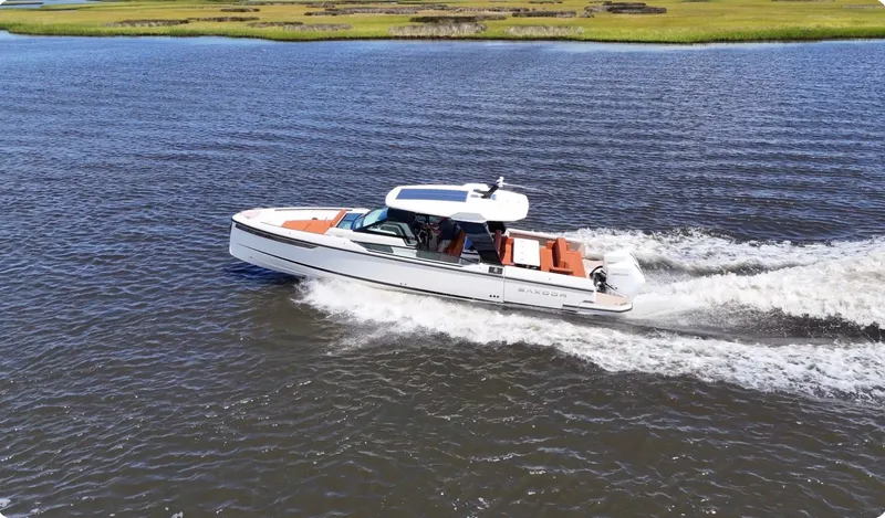 Slide: The Image of A 2027 Saxdor 320 GTO speeds across the water, surrounded by green shores. - 36