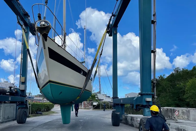 Slide: The Image of Norseman 447 sailboat from 1981 being lifted by a crane under a blue sky. - 13