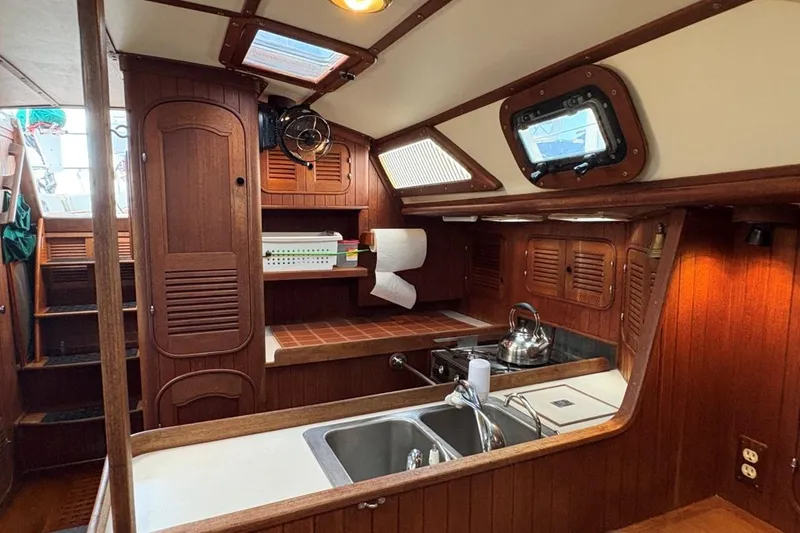 Slide: The Image of Interior of a 1981 Norseman 447 yacht, featuring a wooden kitchen with a sink and stove. - 24