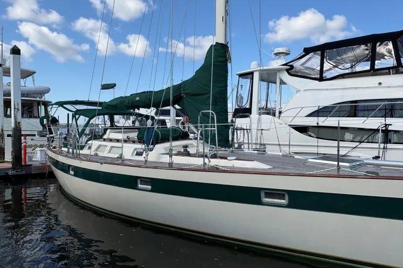 Slide: The Image of 1981 Norseman 447 sailboat docked, featuring green sail covers and sleek design. - 4