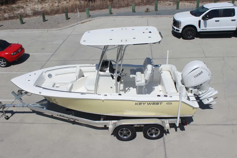 Slide: The Image of 2026 Key West 203 FS boat on trailer, parked beside vehicles in a lot. - 28