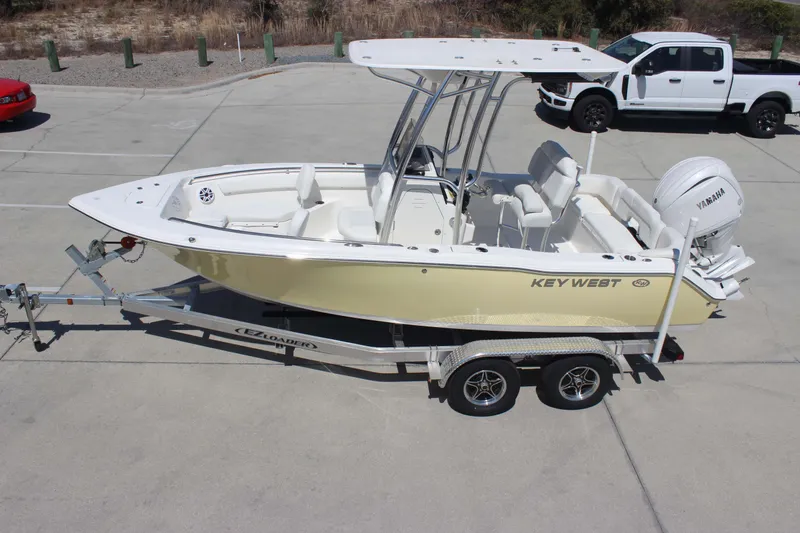 Slide: The Image of 2026 Key West 203 FS boat on trailer, parked in a lot with vehicles nearby. - 32
