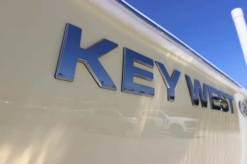 Slide: The Image of Key West 203 FS 2026 boat logo on a sleek, cream-colored hull under clear blue sky. - 6