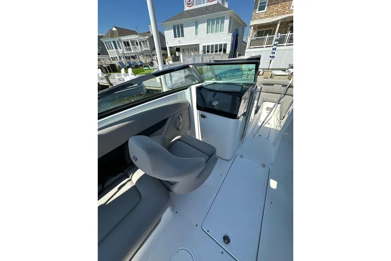 Slide: The Image of 2022 Four Winns HD8 OB boat interior with seating and dashboard, docked near waterfront homes. - 11
