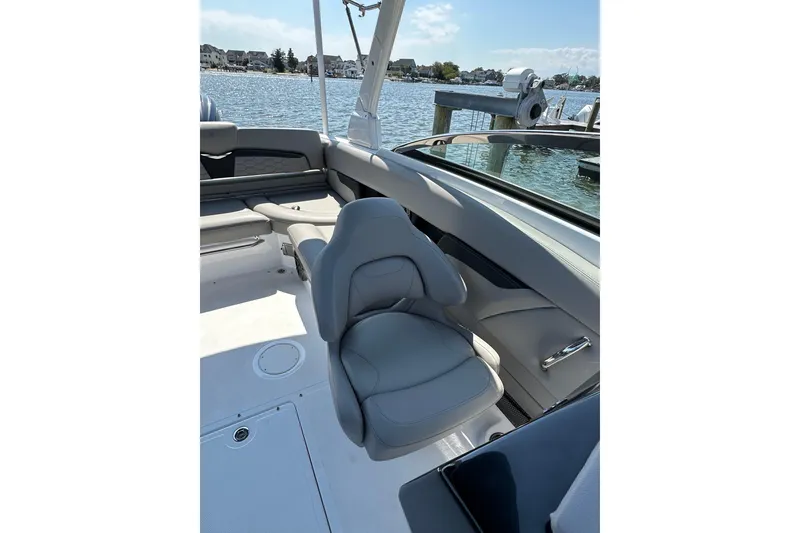 Slide: The Image of 2022 Four Winns HD8 OB boat interior with gray seating, docked by the water. - 12
