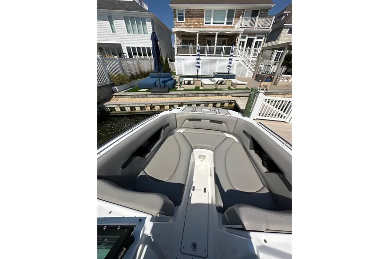 Slide: The Image of 2022 Four Winns HD8 OB boat interior with gray seating, docked near waterfront homes. - 13
