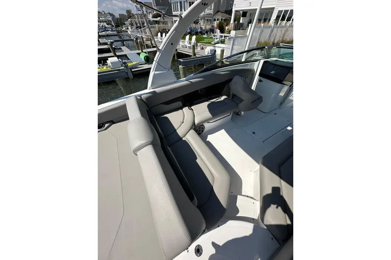 Slide: The Image of 2022 Four Winns HD8 OB boat interior with gray seating at a marina. - 16
