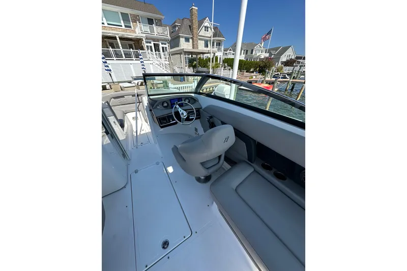 Slide: The Image of 2022 Four Winns HD8 OB boat interior with steering wheel, docked near waterfront homes. - 9