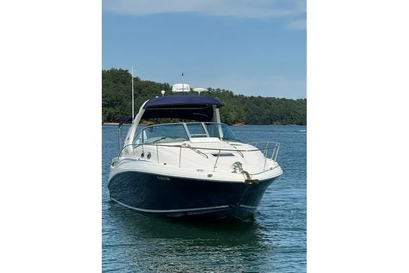 Slide: The Image of 2006 Sea Ray Sundancer 320 yacht on a serene lake with forested shoreline. - 2