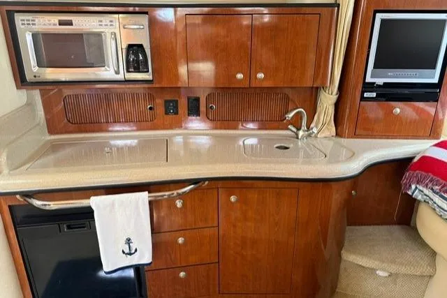 Slide: The Image of 2006 Sea Ray Sundancer 320 interior kitchen with microwave, sink, and wooden cabinetry. - 20