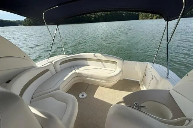 Slide: The Image of 2006 Sea Ray Sundancer 320 boat interior with cushioned seating on a serene lake. - 5