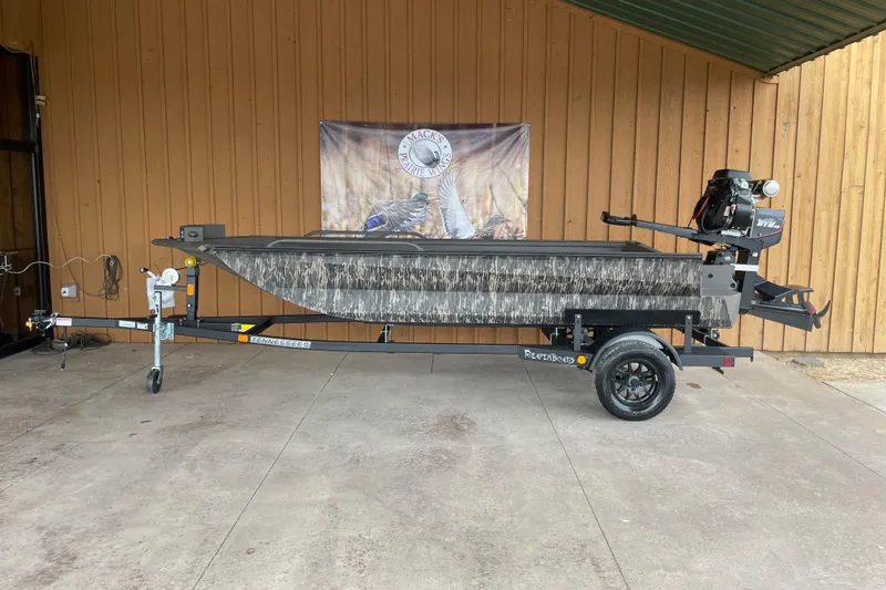 Slide: The Image of 2026 Reaper Boats 653 Timber Reaper on trailer, camo design, displayed indoors. - 2